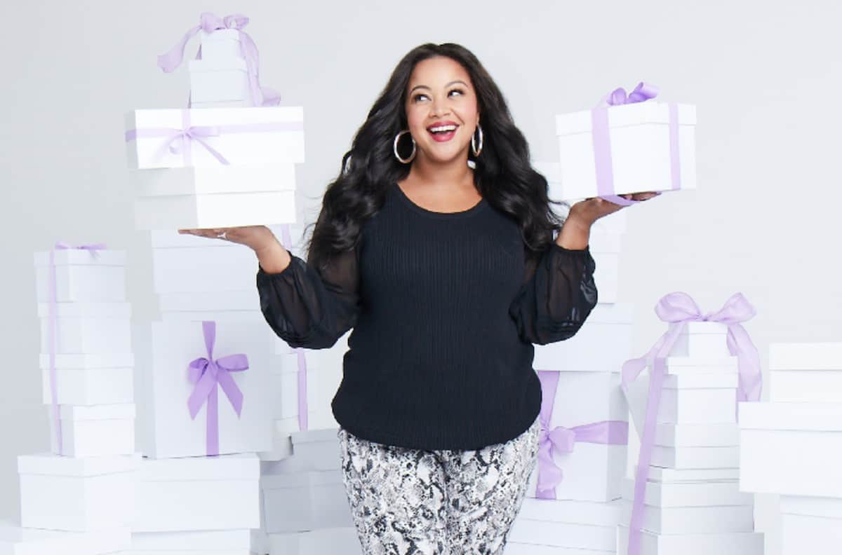 african american woman surrounded by white boxes with purple ribbons from dia&co subscription box styling service