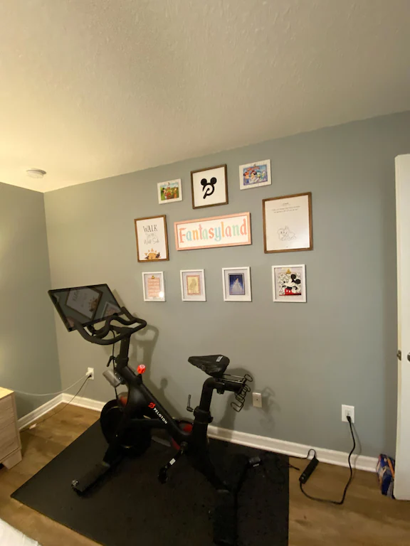 peloton bike in room with disney posters on the wall