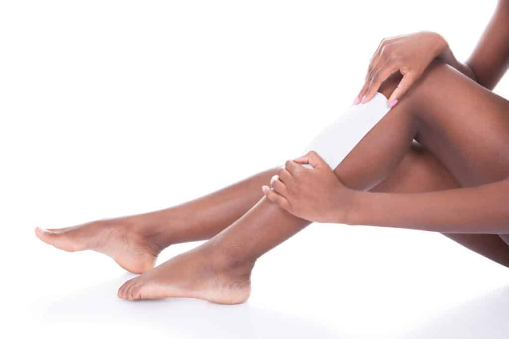 Woman Waxing Legs Against White Background