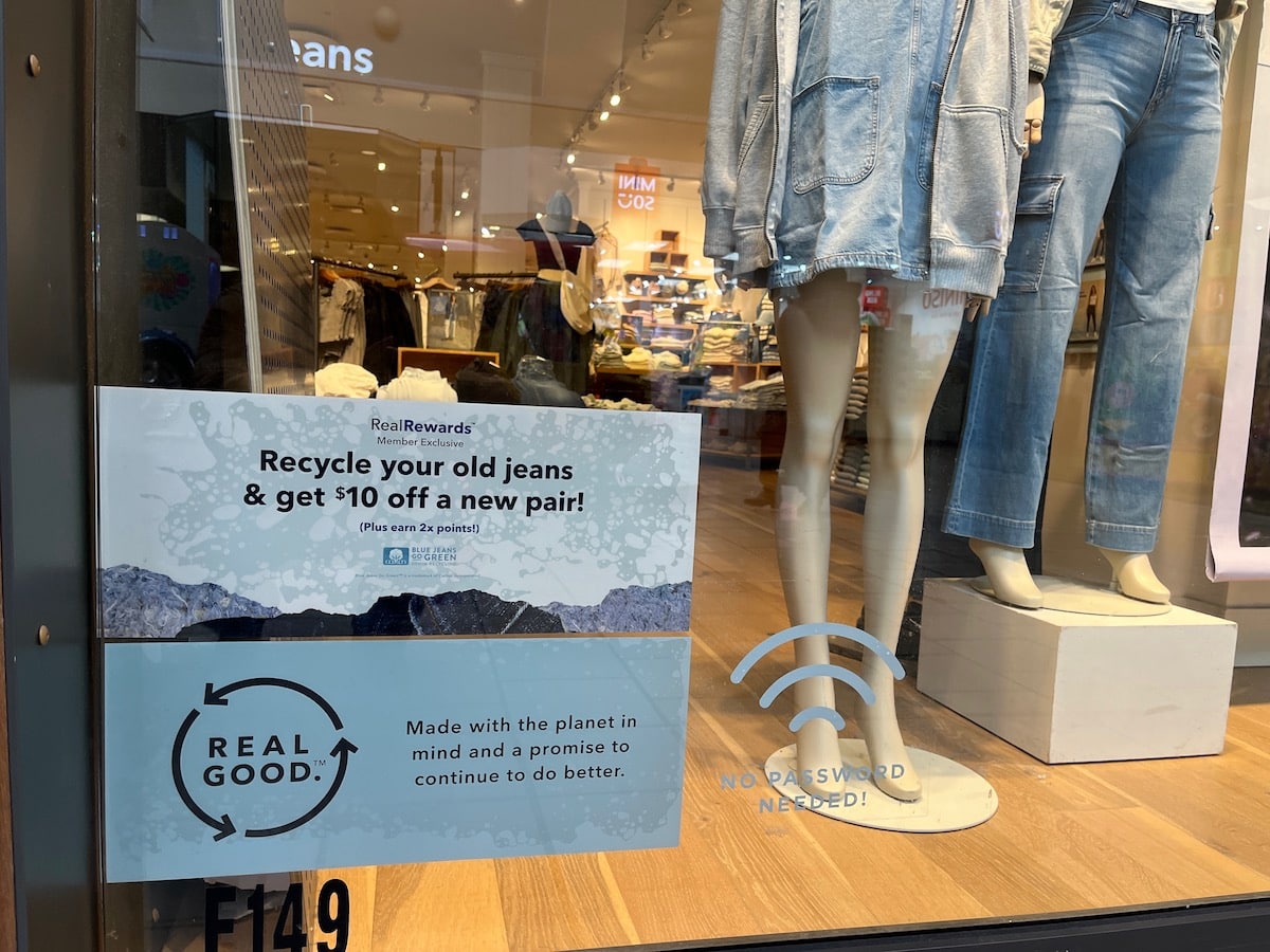 A sign in the window of a clothing store advertises resale programs.