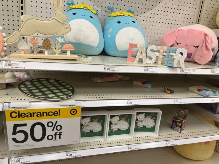 Easter-themed decorations and stuffed animals on a store shelf marked with a 50% off clearance sign for after-Easter sales.