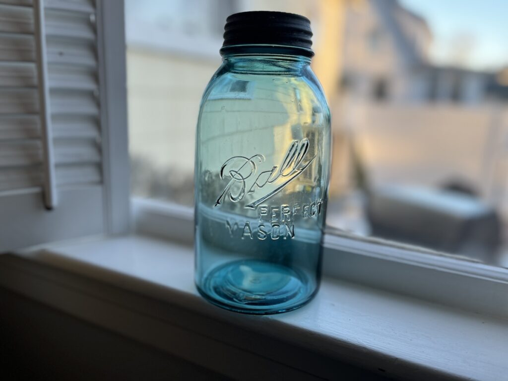 Blue mason jar in front of a window.